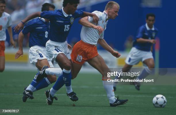 Dutch footballer Dennis Bergkamp makes a penetrating run with the ball between Brazilian players, captain Dunga and Marcio Santos during play in the...