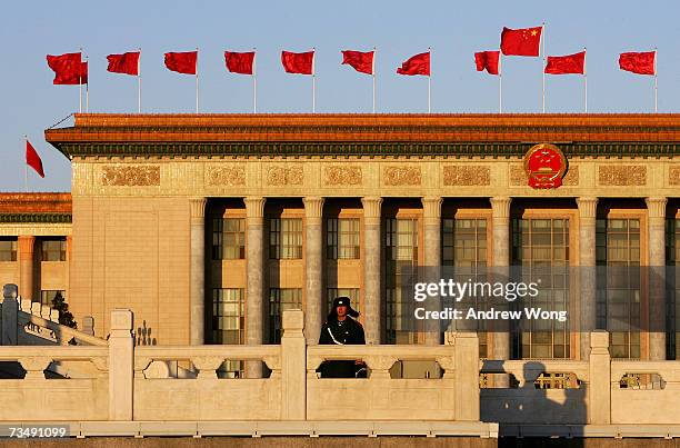 Chinese policeman stands guard in front of the Great Hall of the People during sunrise before the opening session of the National People's Congress,...