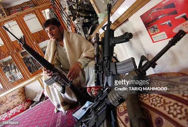 Darra Adamkhel, PAKISTAN: A Pakistani tribal shopkeeper displays an American M-16 and other assault rifles in Darra Adamkhel tribal agency bordering...