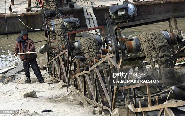 Chinese worker shovels dredged silt caused by deforestation along the Yangtze River, in an attempt to keep the entrance to Poyang lake, which is...