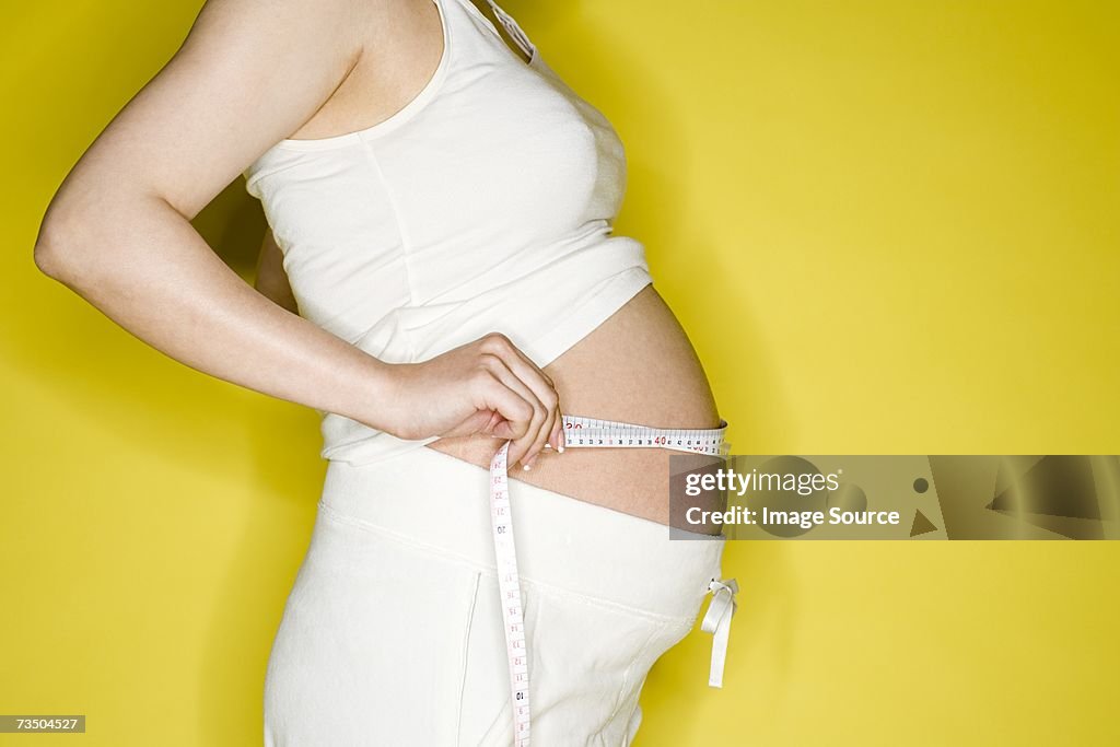 Pregnant woman measuring her stomach