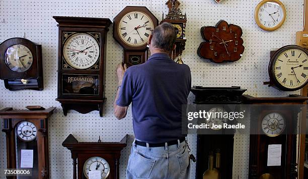 Howard Brown hangs a clock he just repaired on the wall at Brown?s Old Time Clock Shop March 6, 2007 in Plantation, Florida. This year day light...