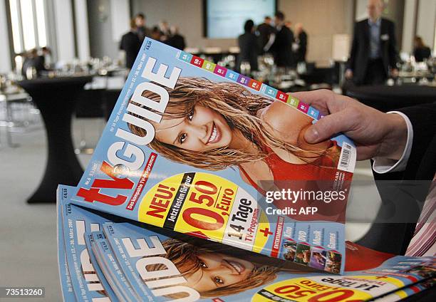An employee of German newspaper publisher Axel Springer gives out copies of their new TV Guide at an annual results press conference in Berlin 07...