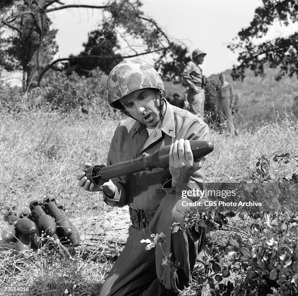 American actor and singer Jim Nabors, in character as Gomer Pyle, kneels and stares in bewilderment at the M28A2 rocket, for the M20 bazooka...