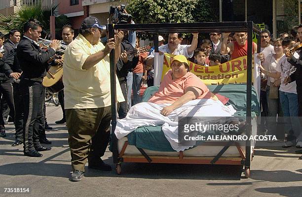 Mexican overweight Manuel Uribe takes a promenade 07 March, 2007 on his bed, accompanied by a mariachi group and friends along the streets of his...