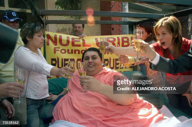 Mexican overweight Manuel Uribe toasts with champaigne on his bed during a promenade 07 March accompanied by a mariachi group and friends along the...