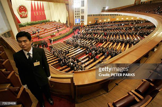Plainclothes policeman stands guard as delegates file out of the Great Hall of the People in Beijing on the fourth day of the National People's...