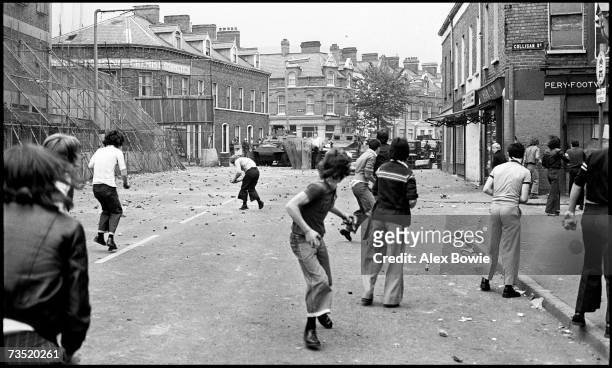 Teenagers throwing stones at the British Army who fire plastic bullets during rioting on the republican Falls Road in Belfast, 17th September 1976....