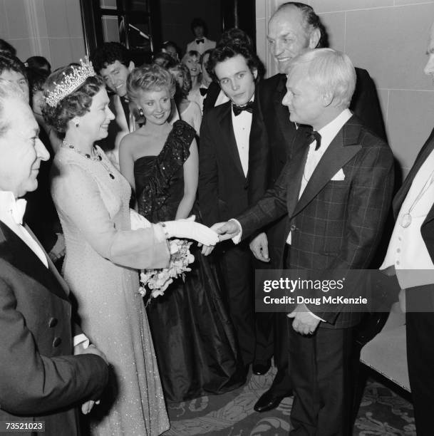 Queen Elizabeth II shakes hands with English comic actor John Inman at the Royal Variety Performance, London, 1981. Left to right: Queen Elizabeth...