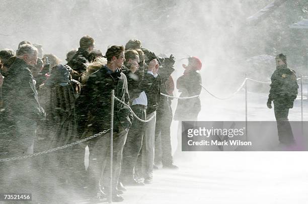 Member of the U.S. Secret Service watches visitors as snow is blown from the helicopter Marine One as it takes off carrying President George Bush on...