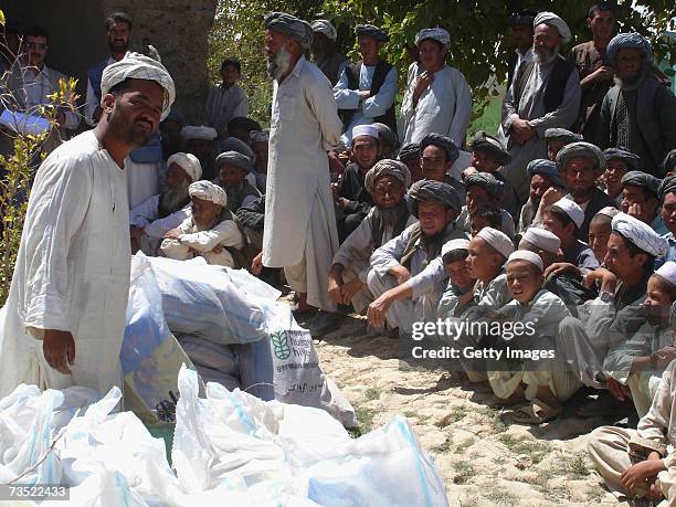 Locals stand beside sacks as German relief organization Welthungerhilfe distributes non-food relief goods on August 28, 2005 near Sari Pul,...