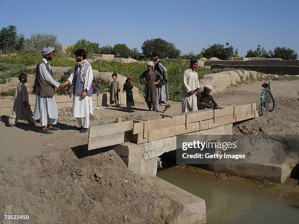 Locals stand on a bridge built by German relief organization Welthungerhilfe as part of a so-called National Solidarity Program on August 28, 2005...
