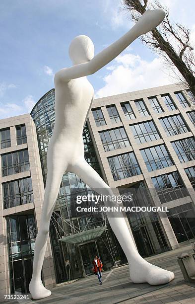 Man walks under US artist Jonathan Borofsky's 17-meter tall "Walking Man" sculpture, in front of German reinsurance giant Munich RE's headquarters in...