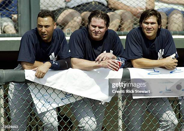 Derek Jeter, Jason Giambi and Johnny Damon of the New York Yankees watch play from the dugout against the Atlanta Braves during a Spring Training...