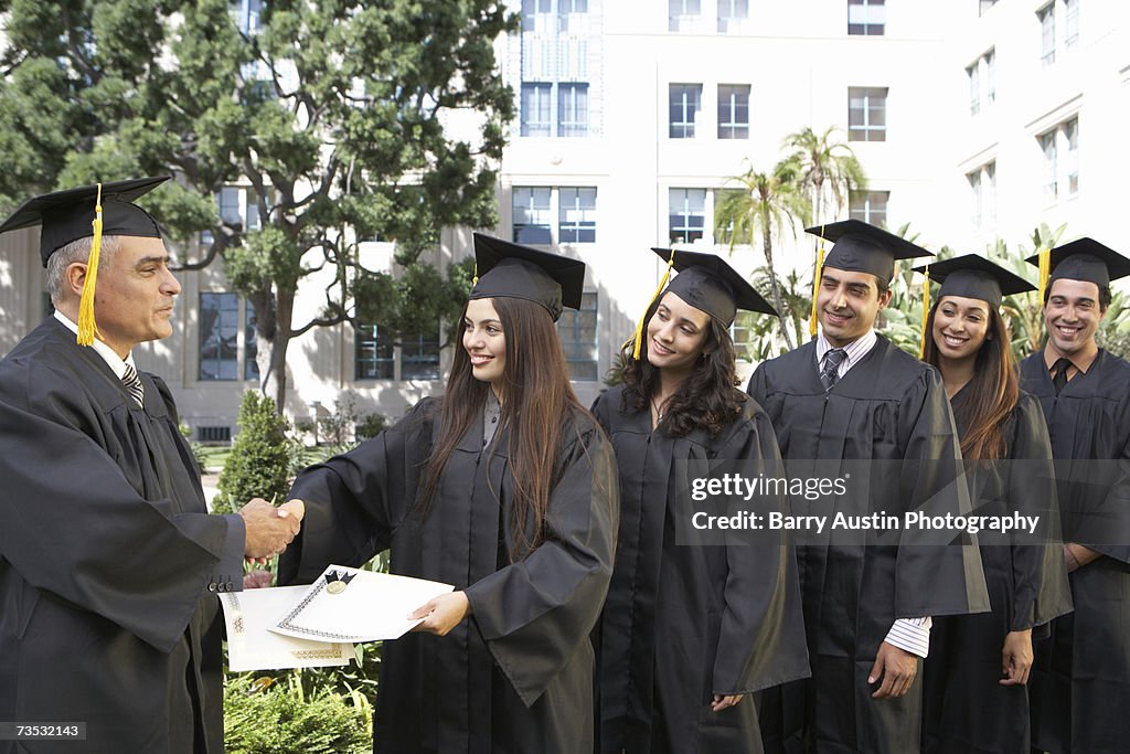 Dean presenting graduate students with awards outside college