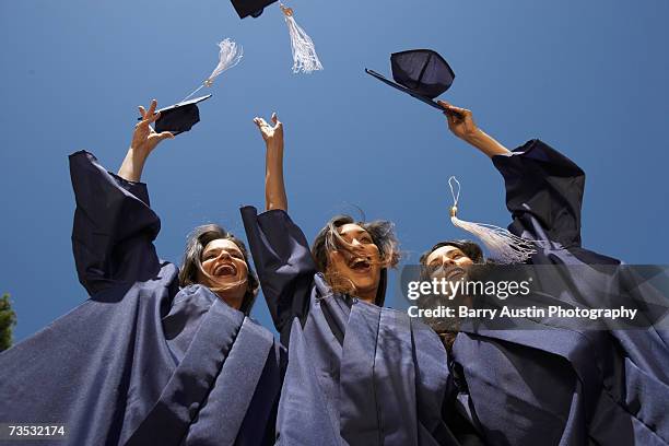 three female graduate students throwing mortar boards, low angle view - examen bildbanksfoton och bilder