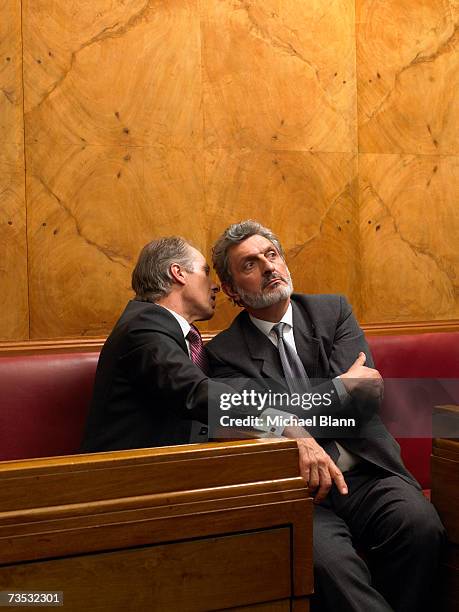 mature man whispering to colleague in pew - fluisteren stockfoto's en -beelden