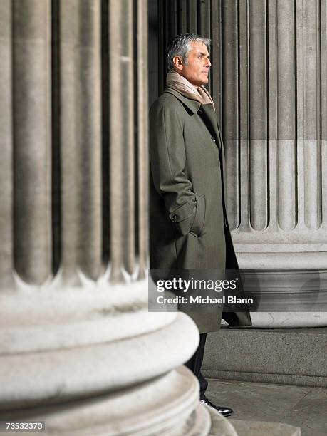 mature man standing outside, in between large columns - grey overcoat stock pictures, royalty-free photos & images