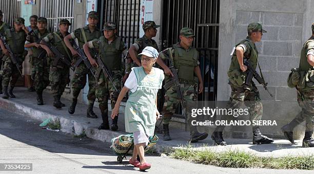 Una mujer camina junto a soldados del Ejercito de Guatemala quienes patrullan el centrico barrio de El Gallito en la zona 3 de Ciudad de Guatemala,...