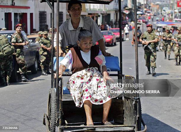 Un vehiculo de transporte de traccion a sangre pasa junto a soldados del Ejercito de Guatemala en el centrico barrio de El Gallito en Ciudad de...