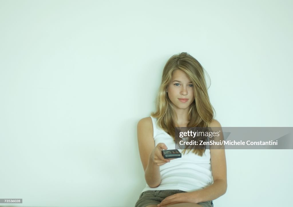 Young woman pointing remote control