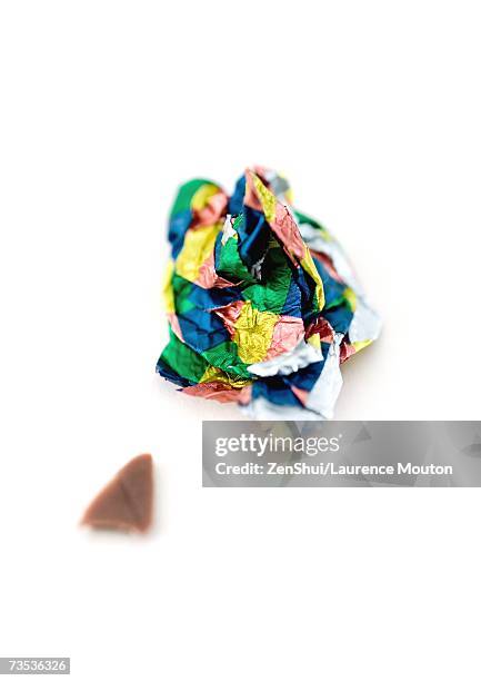 crumpled candy wrapper and small piece of chocolate - chocolate wrapper stock pictures, royalty-free photos & images
