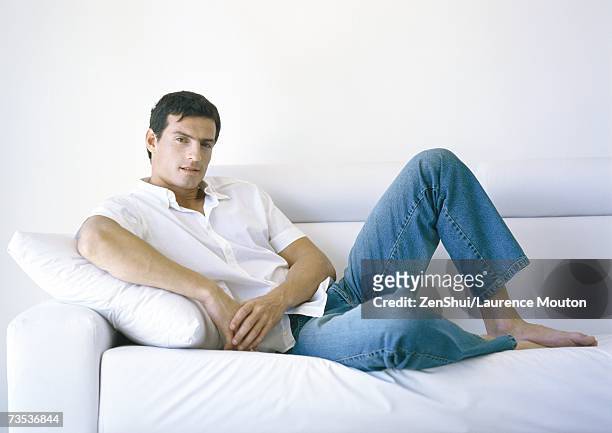 man lounging on sofa - achterover leunen stockfoto's en -beelden