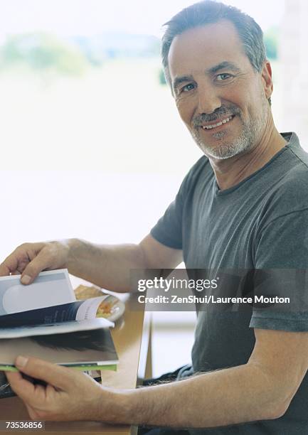 man sitting at table, thumbing through book - at a glance foto e immagini stock