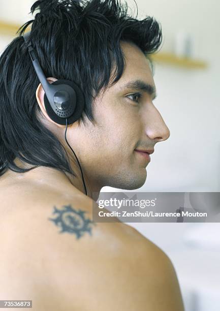 man listening to headphones - tattoo shoulder stock-fotos und bilder