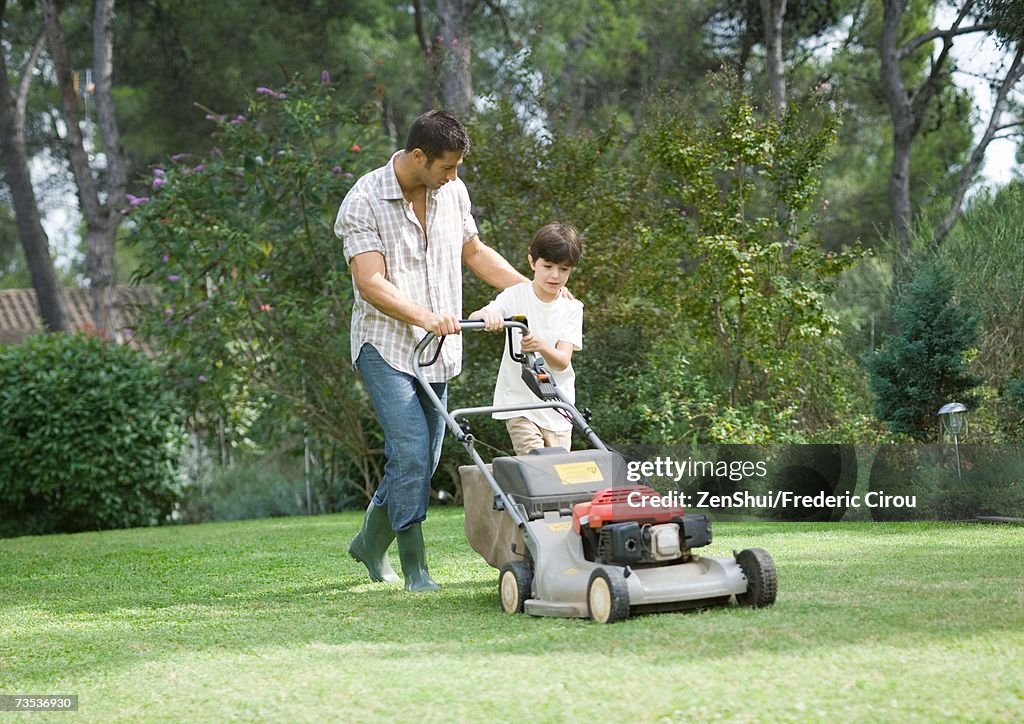 Father and son mowing lawn