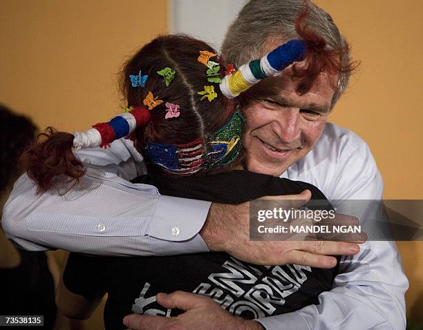 President George W. Bush hugs a dancer who has decorated her hair with the flags of the US and Brazil after a performance during a visit to ?Meninos...