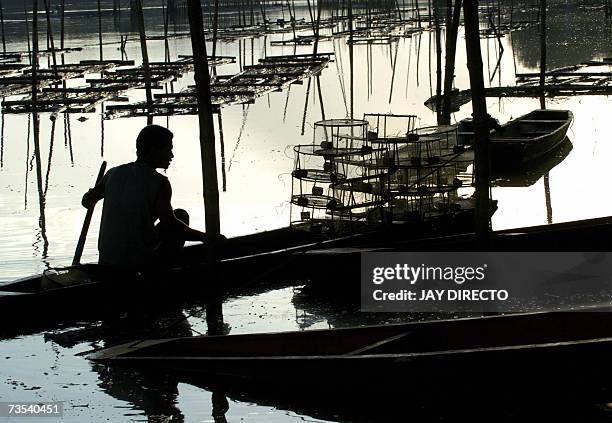 San Isidro, PHILIPPINES: A silhouette of a shrimp trapper is seen after a day of work in the river that passes through San Isidro, Negros Occidental,...