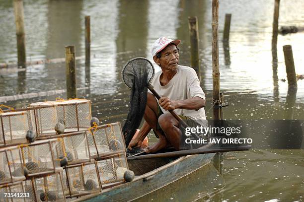 San Isidro, PHILIPPINES: Romeo Istanislao carries some of the shrimps he caught in his traps after a day of work in the river that passes through San...