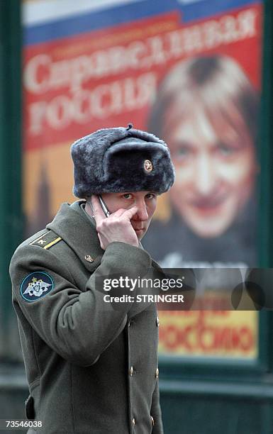 Russian military cadet speaks on a mobile phone near a pre-election poster of "Just Russia" party at a polling station during regional elections in...