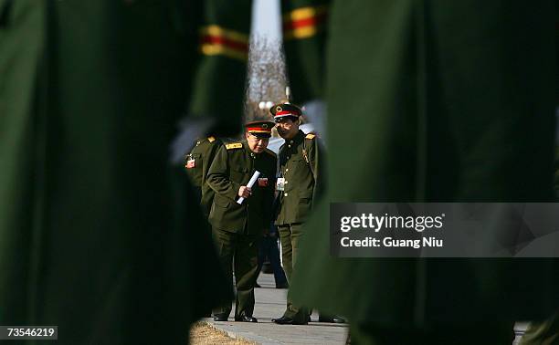 Chinese military delegates chat behind policemen after they attended the third plenary session of the National People's Congress, or parliament, at...