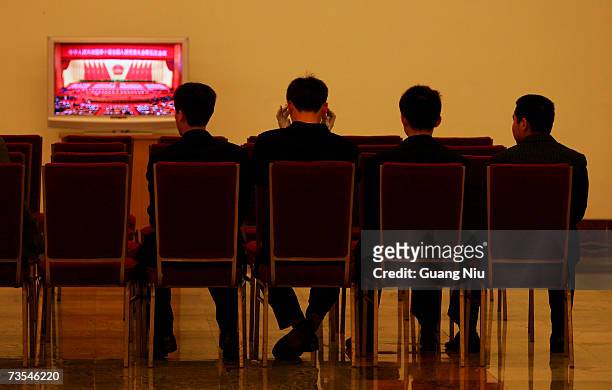 Chinese plainclothes soldiers watch a live TV on the third plenary session of the National People's Congress, or parliament, at the Great Hall of the...