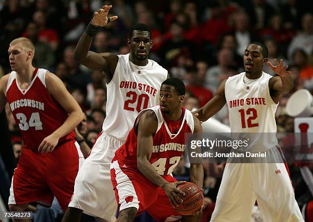 Alando Tucker of the Wisconsin Badgers looks to pass as he is defended by Greg Oden and Ron Lewis of the Ohio State Buckeyes during the Final of the...