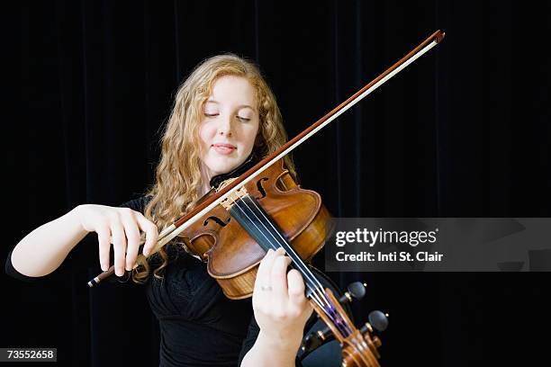 young woman playing violin on stage, close-up - classical musician stock pictures, royalty-free photos & images