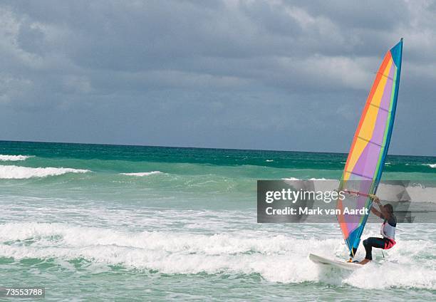 windsurfer riding shore breakers with dark clouds in background - windsurfbrett stock-fotos und bilder