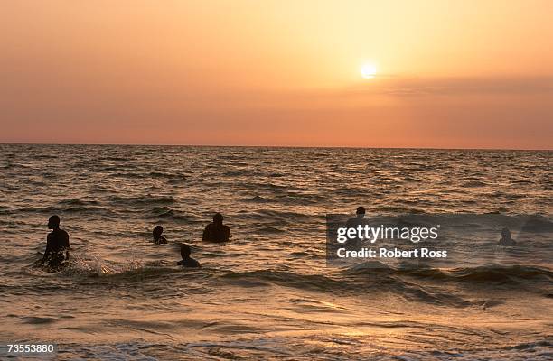 swimmers playing in the surf at sunset - libreville stock pictures, royalty-free photos & images