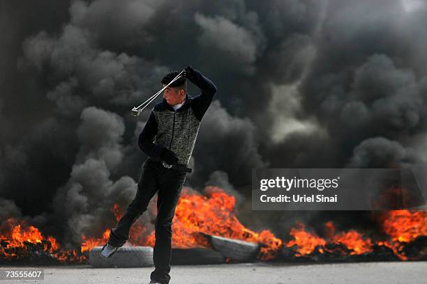 Palestinian youth throws stones at Israeli soldiers during clashes at an Israeli military checkpoint between Jerusalem and the West Bank city of...