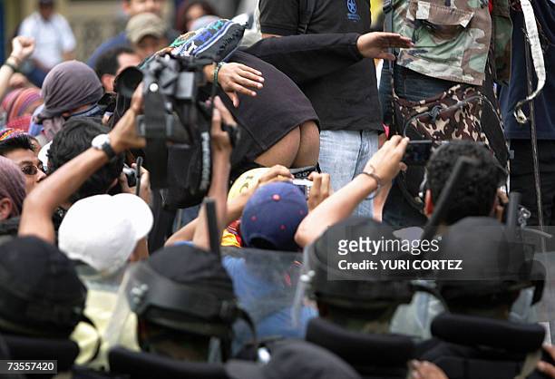 Guatemala City, GUATEMALA: An anti-Bush demonstrator shows his butt0cks to riot police during a protest against the visit of US president George W....