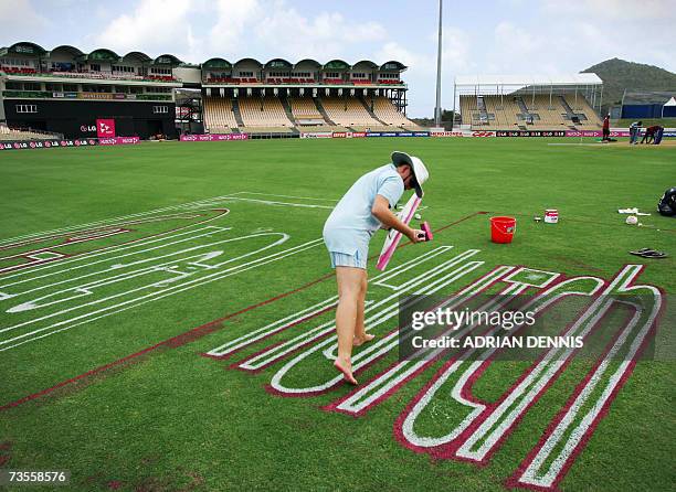 Gros Islet, SAINT LUCIA: A woman steps between letters as she paints an advertising logo onto the outfield at Beausejour Cricket Ground in St. Lucia,...