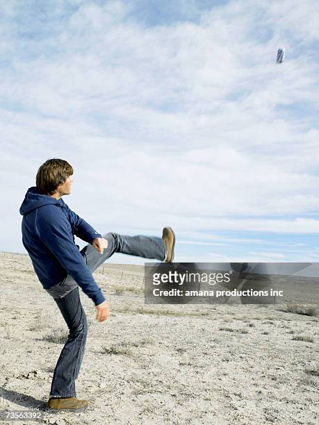 mid adult man kicking beer can in desert - kicking can stock pictures, royalty-free photos & images