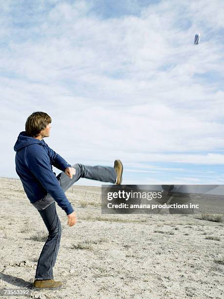 mid adult man kicking beer can in desert - blocked kick stock pictures, royalty-free photos & images