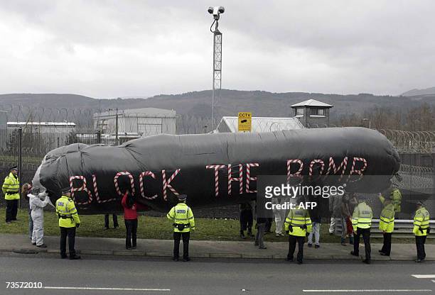 Faslane, UNITED KINGDOM: Campaigners hold an inflatable during a protest in front of the Trident submarine fleet naval base in Faslane, Scotland, 14...