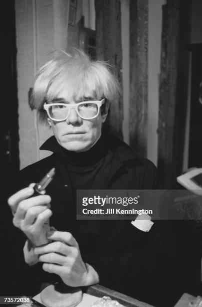 American pop artist Andy Warhol holding a lipstick, circa 1985.