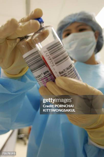 Thai officer inspects test blood bottles during the stem cells process at Stem Life Company in Bangkok, 01 March 2007. Thai parents often mark the...