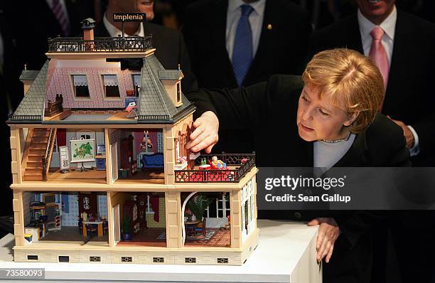 German Chancellor Angela Merkel looks into a dollhouse representing an eco-friendly, microchip-equipped house at the IBM stand while touring the...