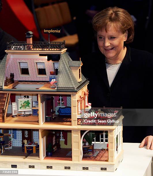 German Chancellor Angela Merkel looks into a dollhouse meant to represent an eco-friendly, microchip-equipped house at the IBM stand while touring...